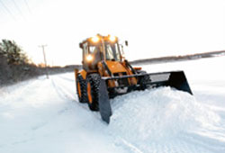 Экскаватор погрузчик JCB 3CX очищает дорогу от снега